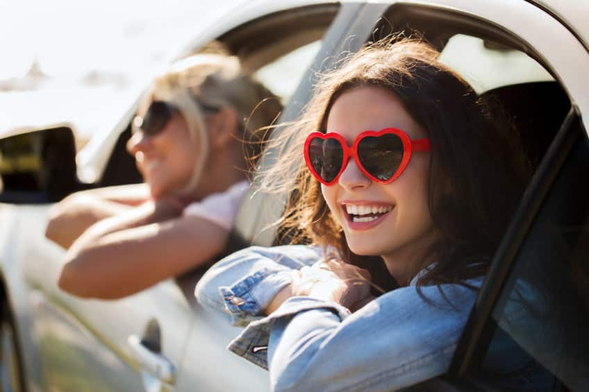 Personnes souriantes en lunettes de soleil dans une voiture.